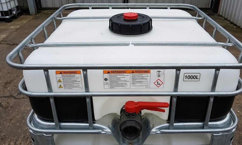 Close-up of an IBC tote cap, valve, and labels showing 1000-liter capacity
